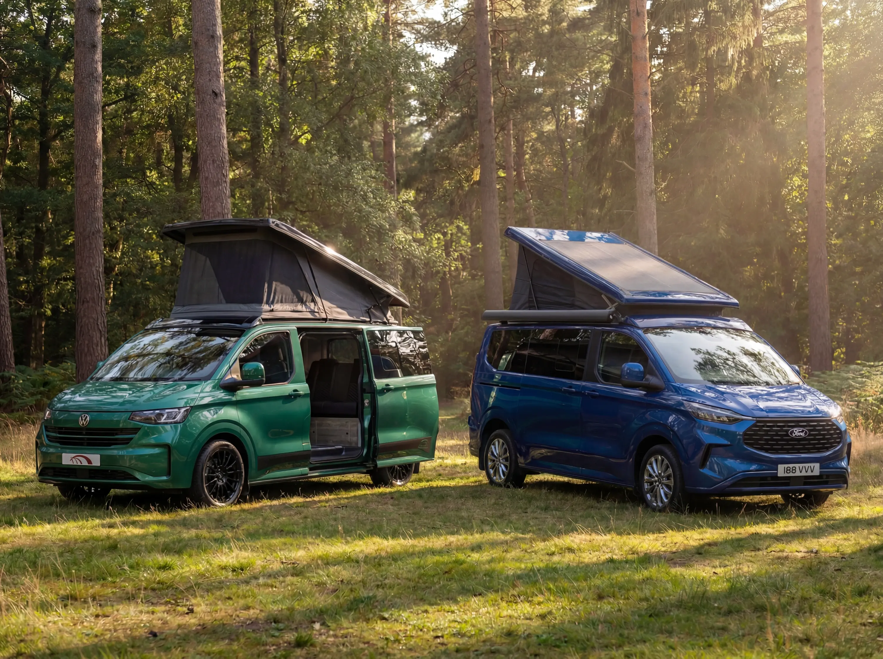 Green Volkswagen and blue Ford camper vans with pop-up roofs parked in forest clearing.