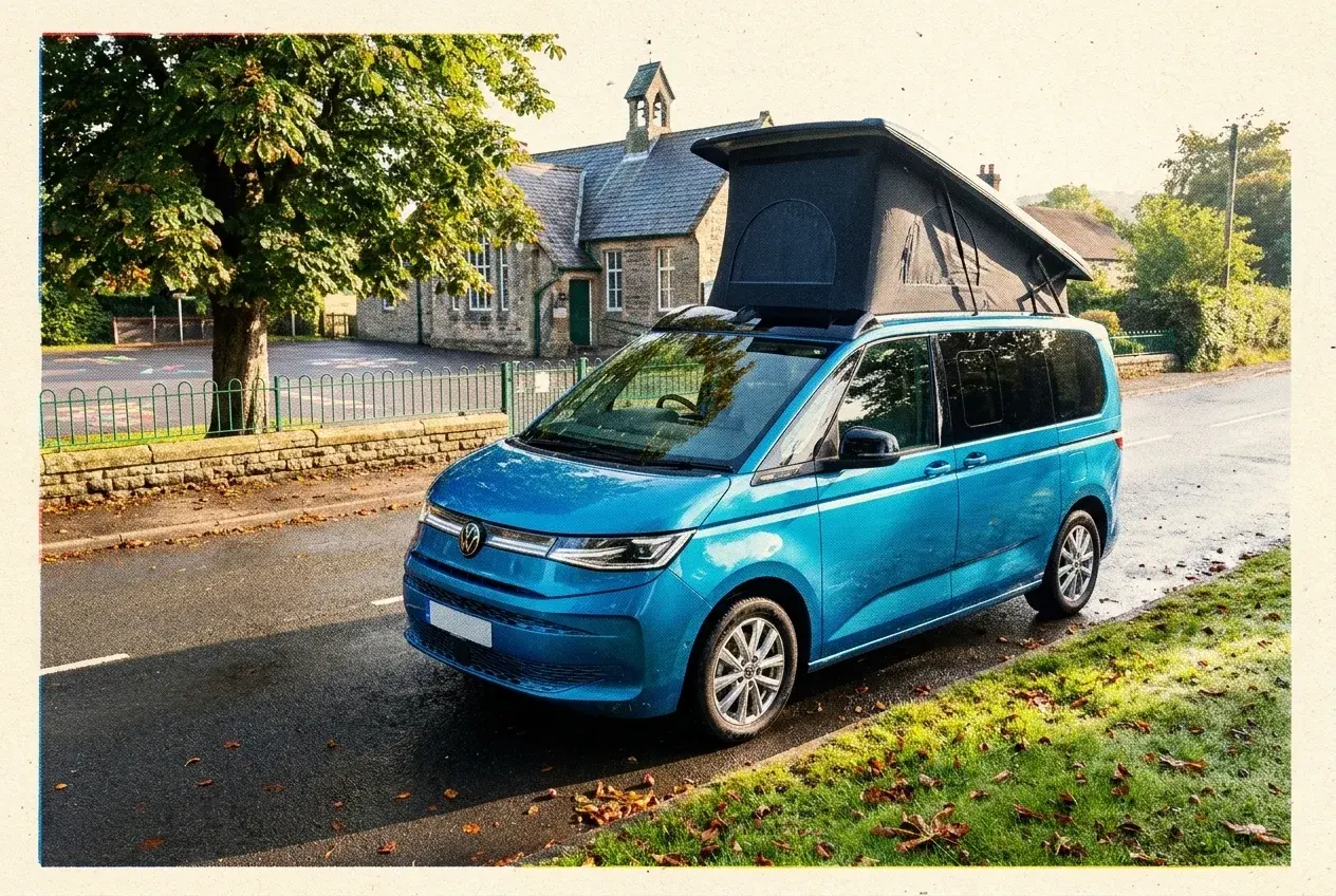 A Hillside MVX pop-top camper on a VW Multivan, roof closed, parked outside a Derbyshire village school on a bright autumn morning.