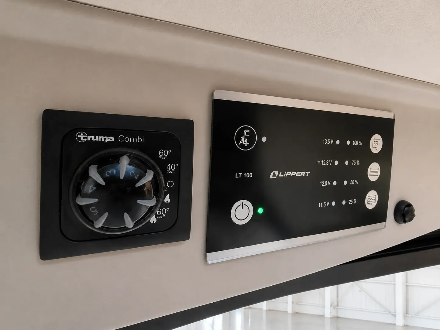 Campervan interior wall-mounted control panels including Truma Combi heating unit and Lippert battery management system.