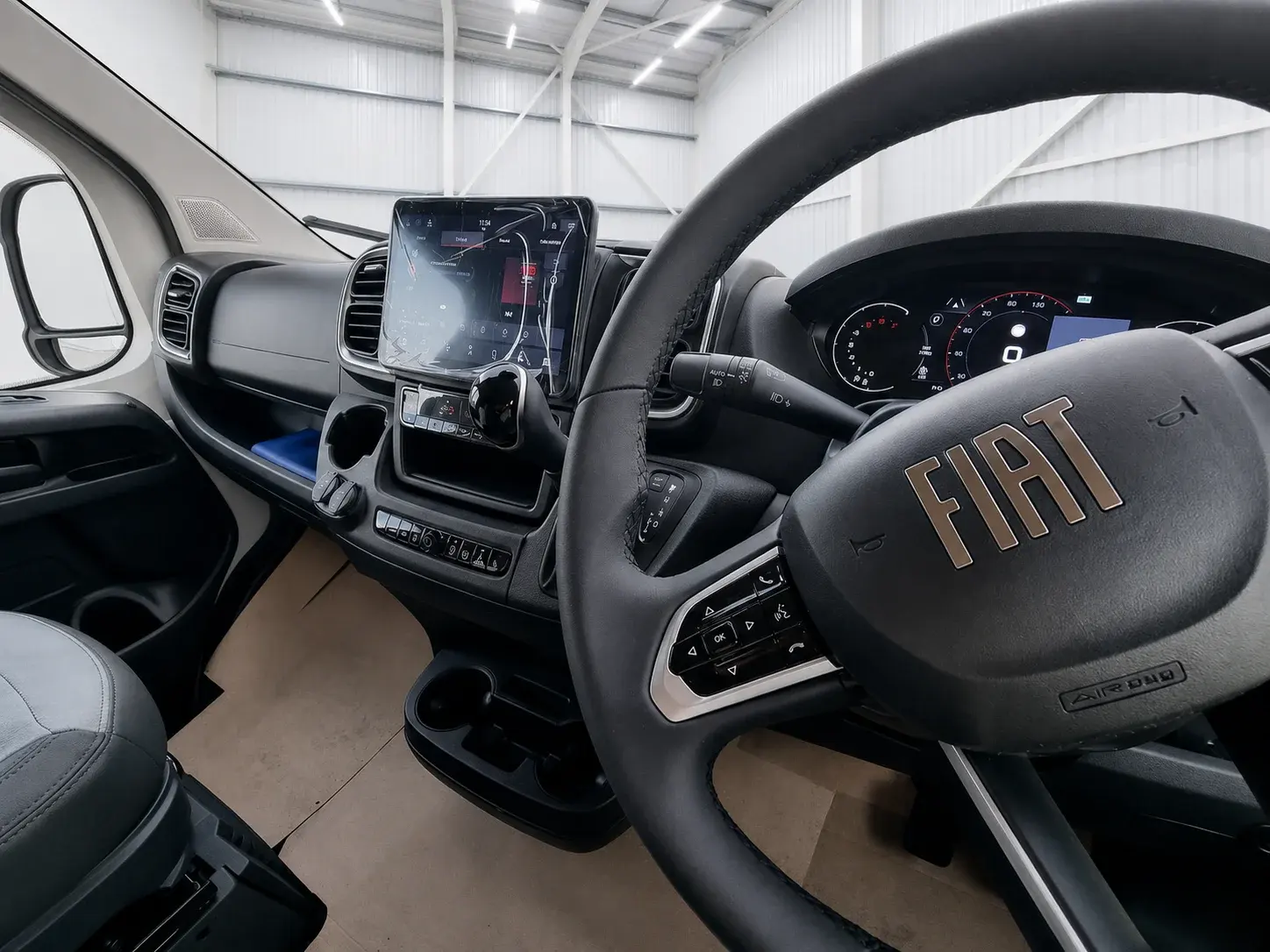 Fiat campervan cockpit interior with steering wheel, touchscreen display, and dashboard controls visible.